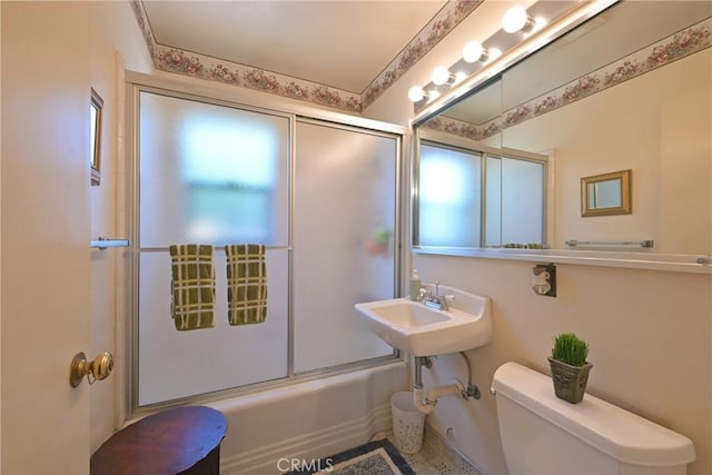 full bathroom featuring shower / bath combination with glass door, a sink, and toilet