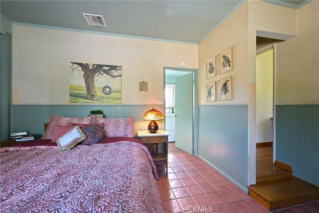 tiled bedroom featuring visible vents, crown molding, and wainscoting