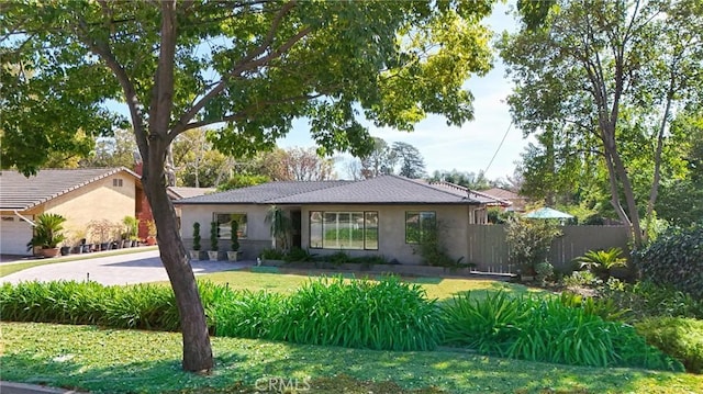 single story home with a front yard, fence, driveway, and stucco siding