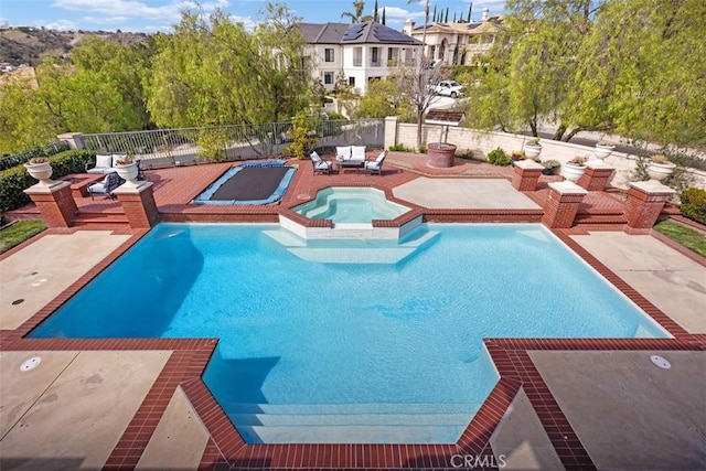 view of swimming pool featuring a patio area, a pool with connected hot tub, and fence