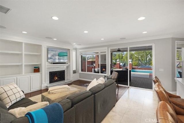 living room with a fireplace, visible vents, a wealth of natural light, and ornamental molding