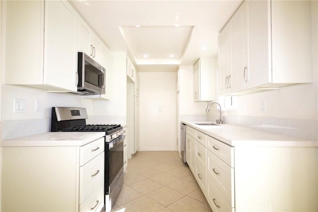 kitchen with light tile patterned floors, a sink, white cabinetry, light countertops, and appliances with stainless steel finishes