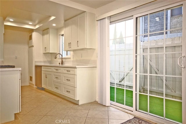 kitchen with recessed lighting, light tile patterned floors, light countertops, white cabinets, and a sink