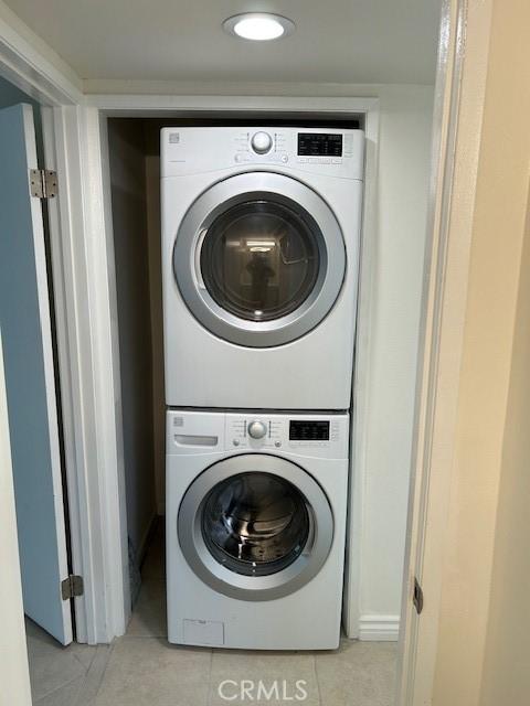 laundry room with light tile patterned floors, stacked washer / drying machine, and laundry area