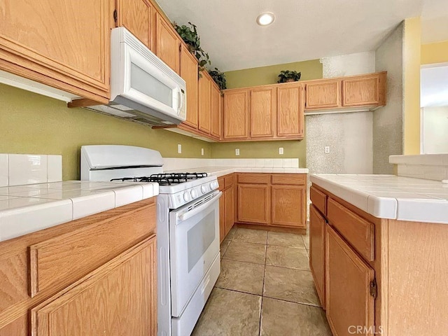 kitchen with white appliances, light tile patterned flooring, and tile counters