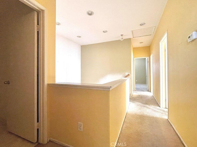 hall with baseboards, light carpet, and an upstairs landing