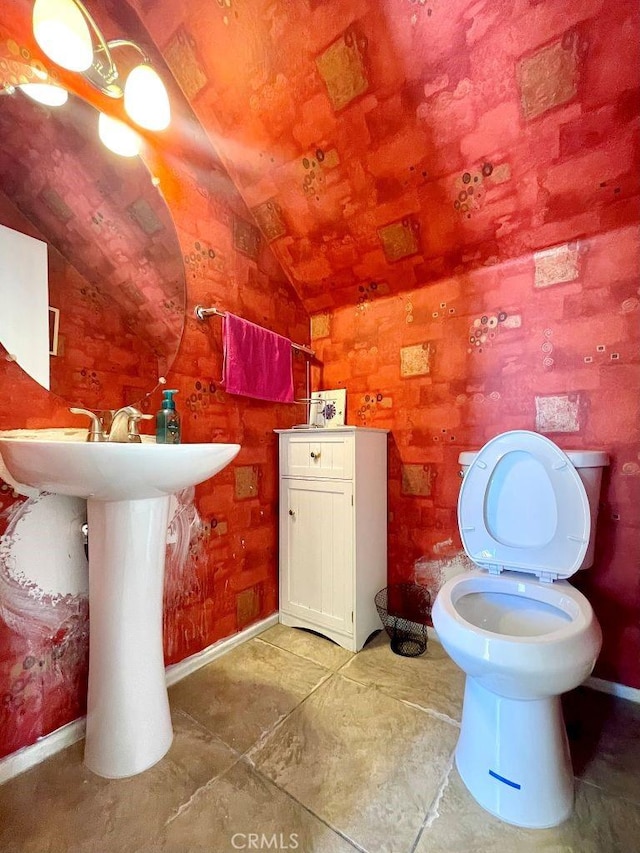 half bath featuring baseboards, vaulted ceiling, and toilet