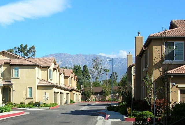 view of street featuring a mountain view, curbs, sidewalks, and a residential view