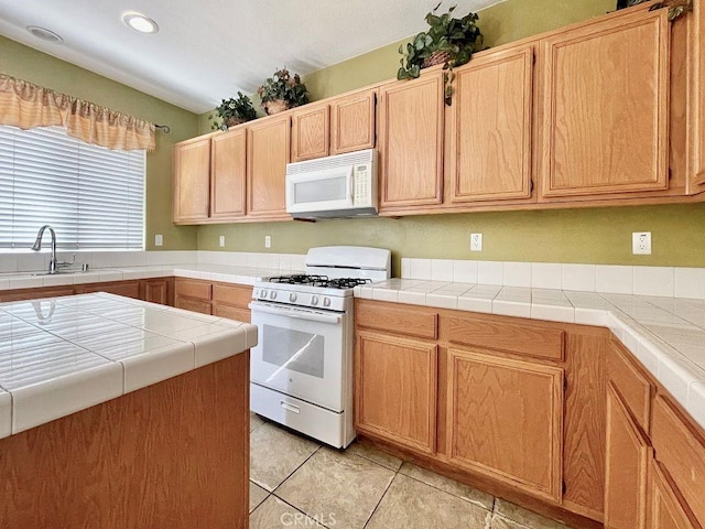 kitchen featuring white appliances, light tile patterned floors, tile counters, and a sink