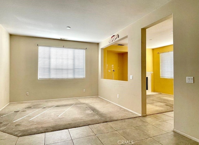 tiled empty room featuring a fireplace and carpet flooring