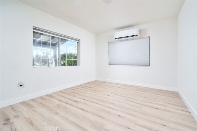 spare room featuring baseboards, wood finished floors, and a wall mounted AC