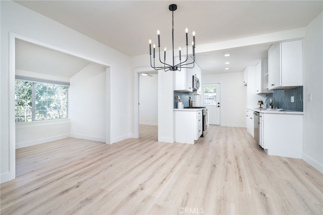 kitchen featuring a sink, stainless steel appliances, light wood-style floors, white cabinetry, and backsplash