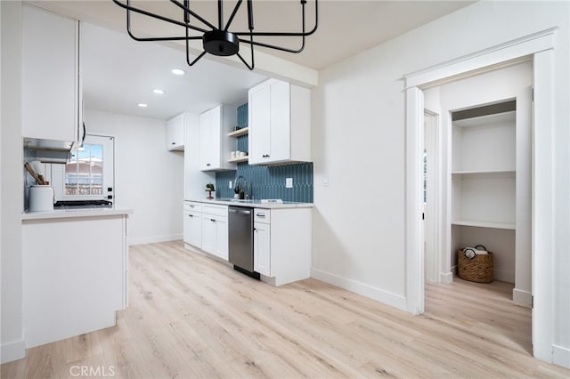 kitchen with white cabinetry, light wood-style floors, light countertops, stainless steel dishwasher, and tasteful backsplash