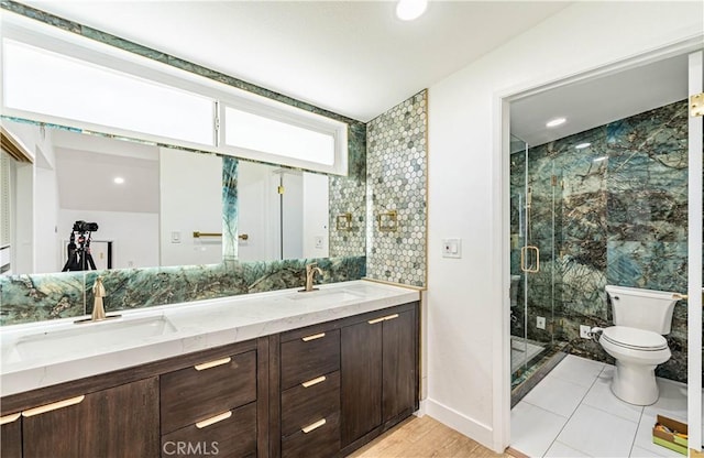 bathroom featuring a stall shower, a sink, toilet, and double vanity