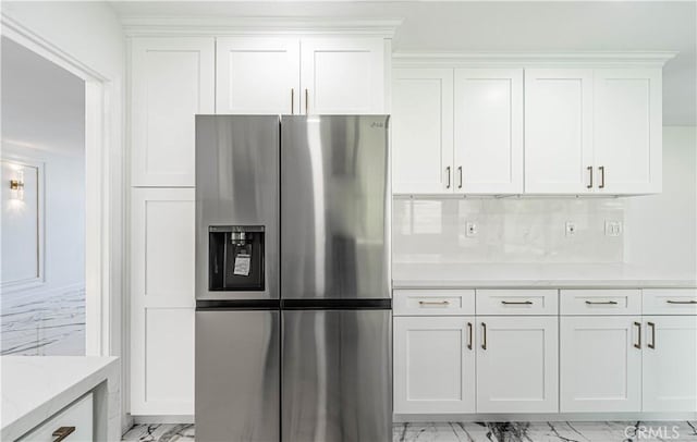 kitchen featuring tasteful backsplash, marble finish floor, stainless steel fridge, and white cabinetry