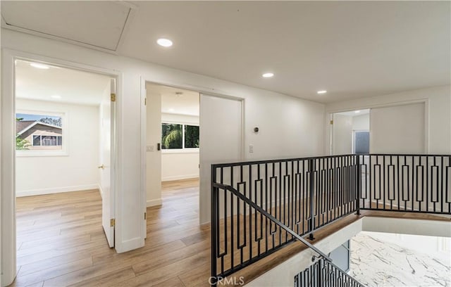 hallway with recessed lighting, plenty of natural light, an upstairs landing, and wood finished floors