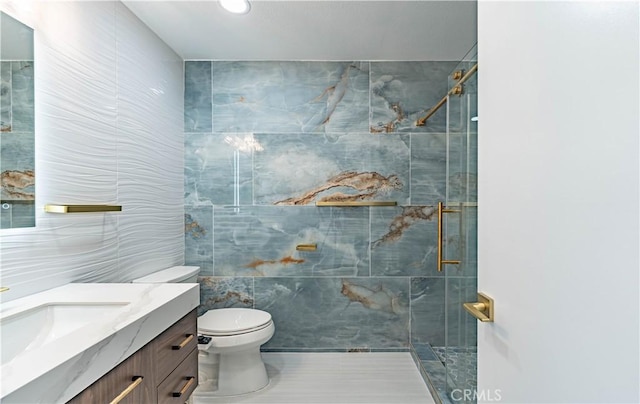 bathroom with toilet, vanity, a shower stall, and tile walls