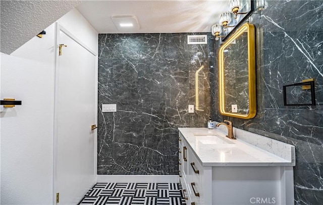 bathroom with tile walls, visible vents, and vanity