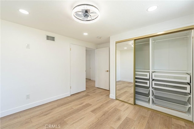 unfurnished bedroom featuring light wood finished floors, a closet, visible vents, and baseboards