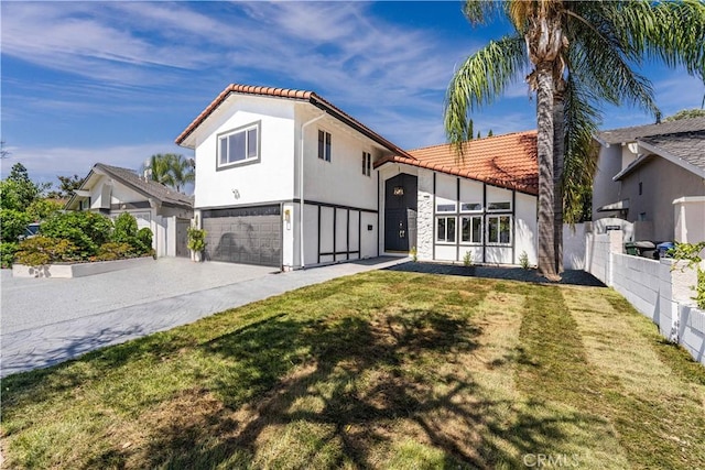 view of front facade featuring a tiled roof, an attached garage, fence, a front lawn, and stucco siding