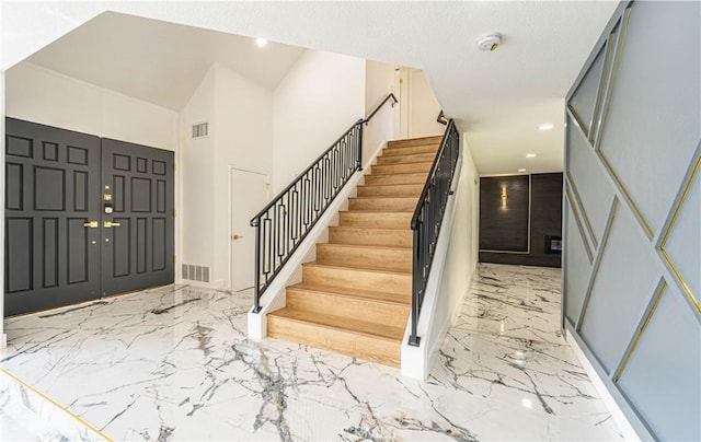 entrance foyer featuring marble finish floor, visible vents, and stairs