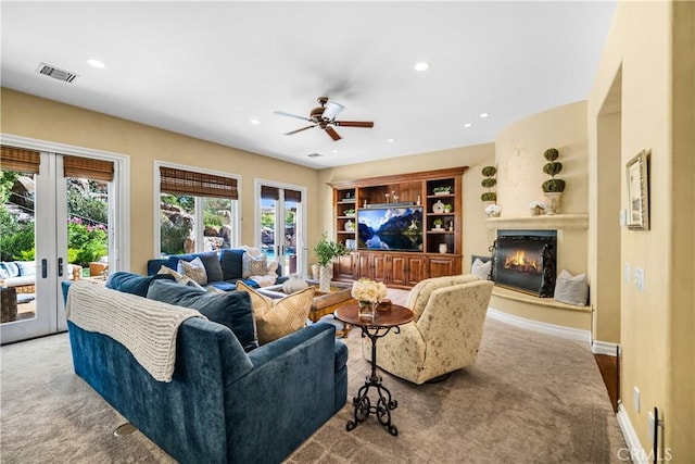 carpeted living room with french doors, recessed lighting, visible vents, a glass covered fireplace, and baseboards