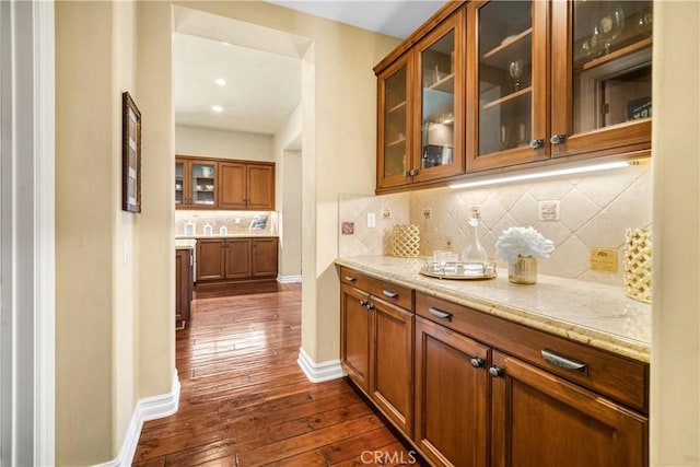 bar featuring dark wood-style floors, baseboards, and tasteful backsplash