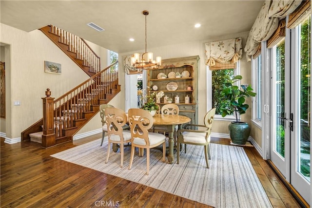 dining space with a chandelier, wood-type flooring, visible vents, and stairs