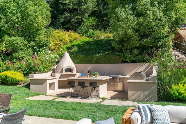 view of patio / terrace with outdoor dry bar, exterior fireplace, and an outdoor kitchen