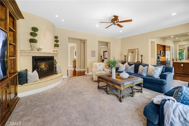 living area with baseboards, a glass covered fireplace, ceiling fan, carpet floors, and recessed lighting