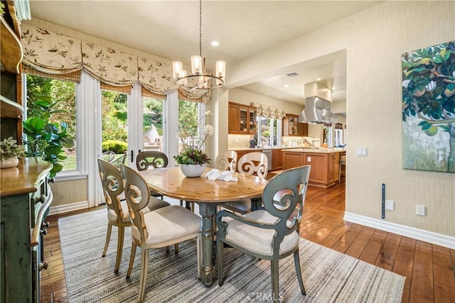 dining area featuring baseboards, hardwood / wood-style flooring, and an inviting chandelier