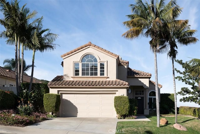 mediterranean / spanish-style home with driveway, an attached garage, a tiled roof, and stucco siding