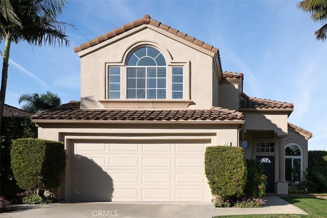 mediterranean / spanish-style home with a garage, a tile roof, concrete driveway, and stucco siding