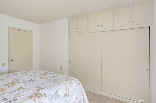 bedroom with light carpet, a textured ceiling, and a closet