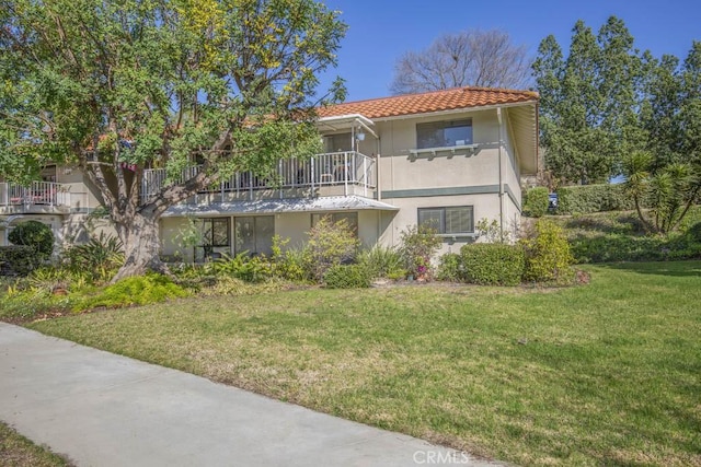 view of front of home featuring a tiled roof, a front lawn, and stucco siding