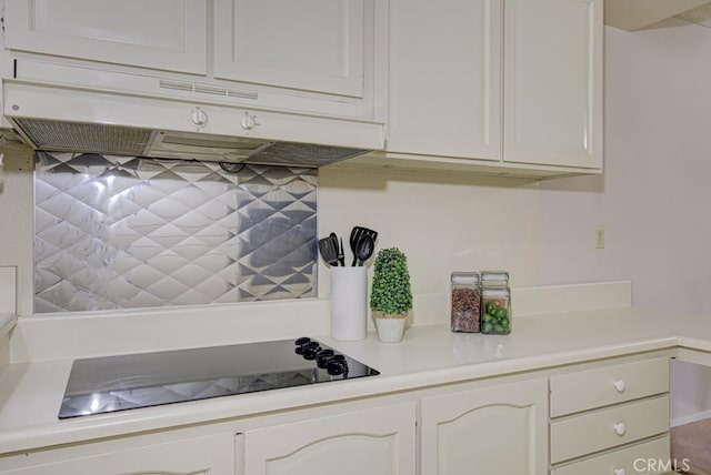 kitchen featuring backsplash, light countertops, under cabinet range hood, and black electric cooktop