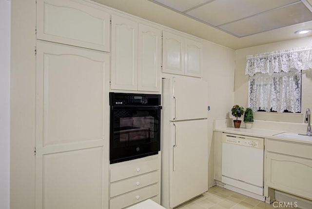 kitchen featuring white cabinets, white appliances, light countertops, and a sink