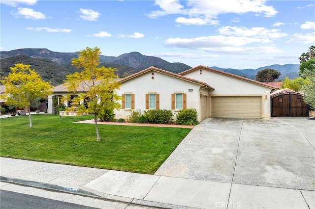 mediterranean / spanish-style house with a garage, concrete driveway, a front yard, a mountain view, and stucco siding