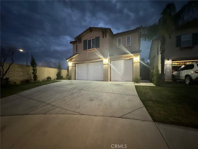 traditional-style house featuring driveway, fence, and stucco siding