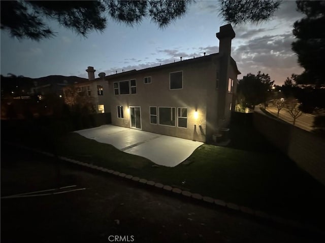 back of property with stucco siding and a patio