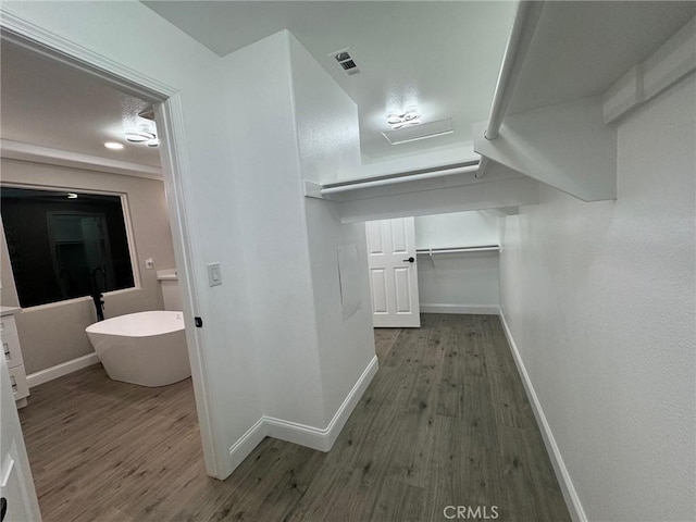 corridor featuring wood finished floors, visible vents, and baseboards