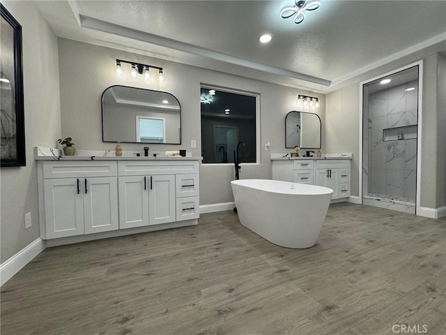 full bathroom with a marble finish shower, a tray ceiling, and wood finished floors