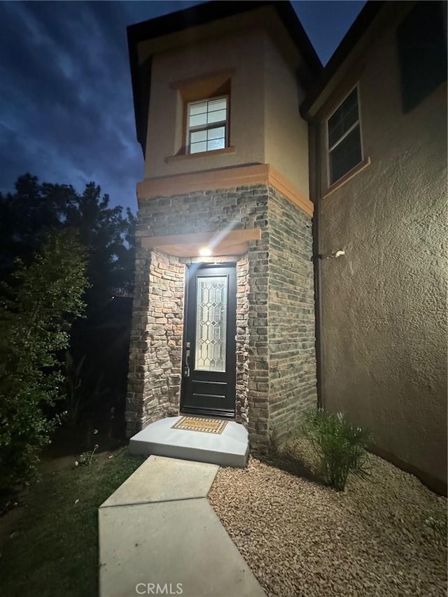 doorway to property with stone siding and stucco siding