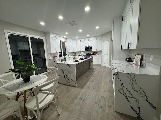 kitchen with a center island, recessed lighting, visible vents, appliances with stainless steel finishes, and light wood-style floors