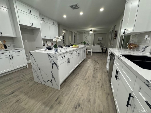 kitchen featuring a center island, light wood finished floors, visible vents, a ceiling fan, and open floor plan