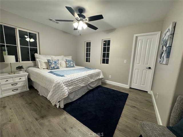 bedroom featuring ceiling fan, dark wood-type flooring, visible vents, and baseboards