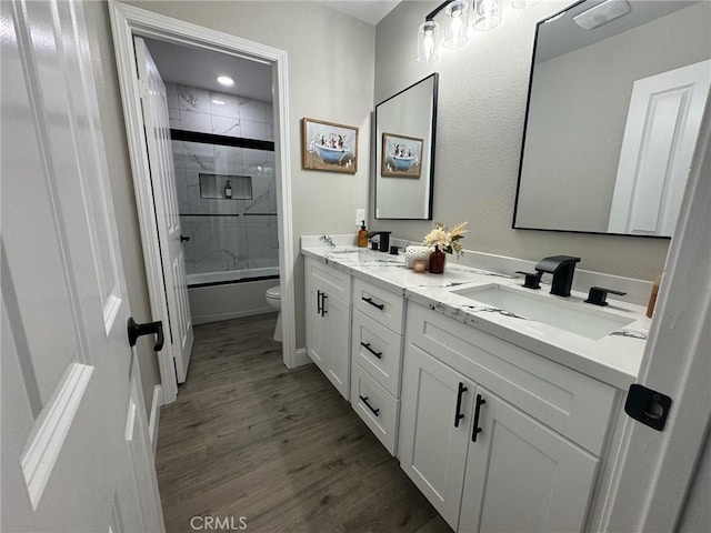 full bathroom featuring toilet, double vanity, a sink, and wood finished floors