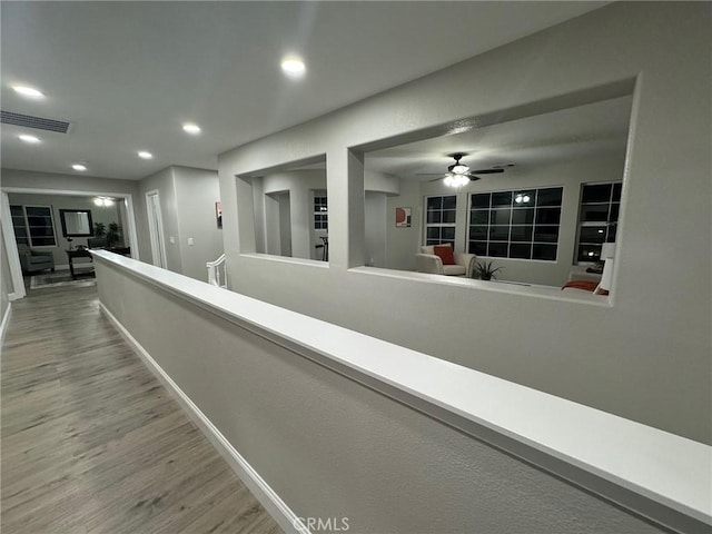 corridor with baseboards, visible vents, wood finished floors, and recessed lighting