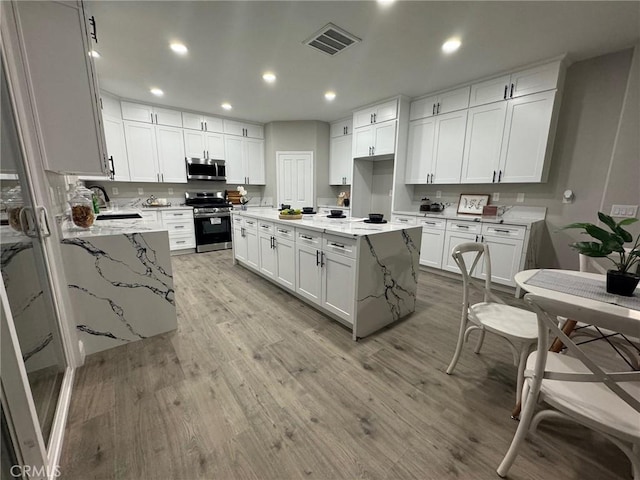 kitchen featuring light wood-type flooring, white cabinetry, visible vents, and appliances with stainless steel finishes