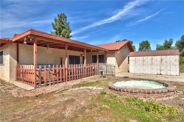 rear view of house with a tiled roof, fence, and stucco siding